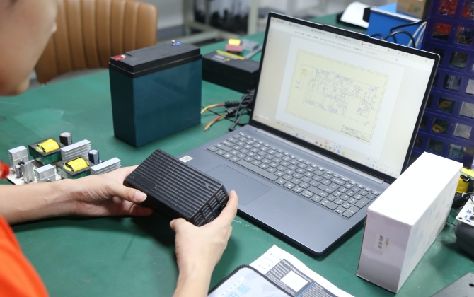 Custom battery charger R&D with engineers reviewing PCB layouts, prototypes and test equipment for ODM development. 
