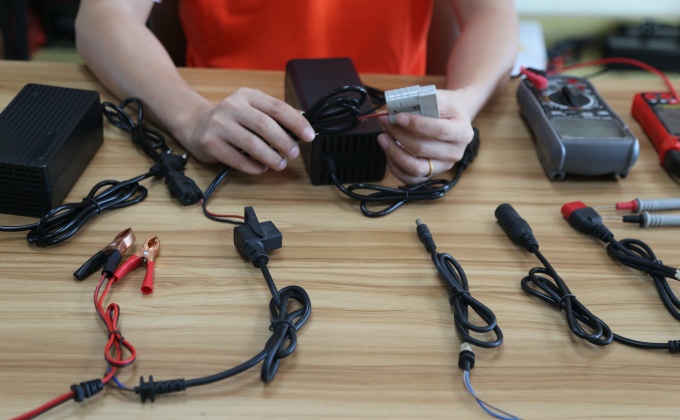 Technician checking a battery charger cable connector for OEM matching
