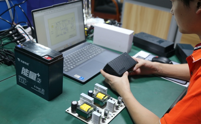 Engineer evaluating battery charger PCBA and battery setup during product development
