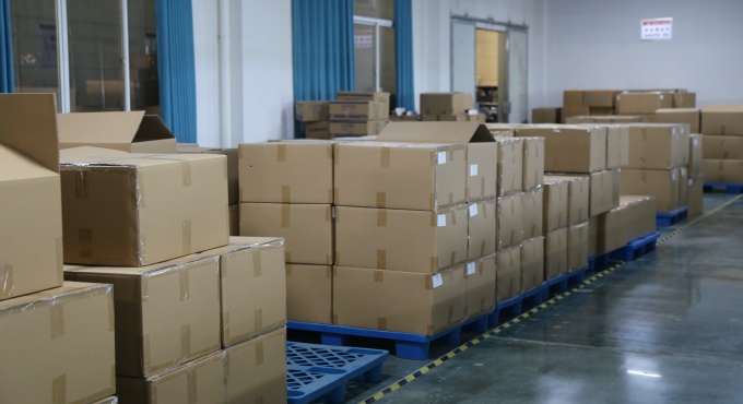 Packed battery charger cartons stored on pallets in the finished goods area
