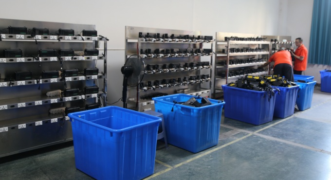 Battery chargers connected on racks for full-load burn-in testing before packing
