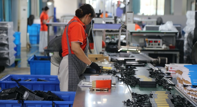 Worker arranging finished battery chargers before packing
