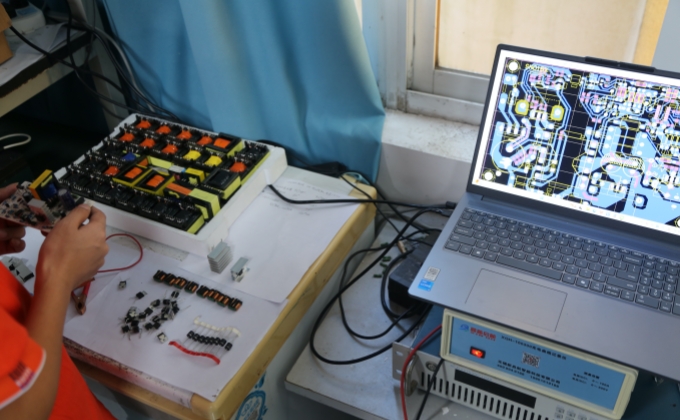 Engineer checking a battery charger PCBA against the PCB layout during engineering verification
