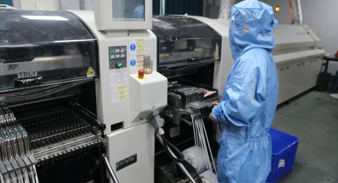 SMT operator running component placement equipment for battery charger PCBA production
