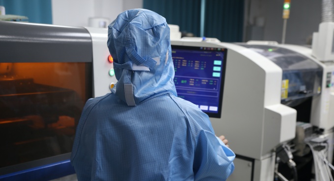 Operator monitoring automatic solder paste printing for battery charger PCBA production
