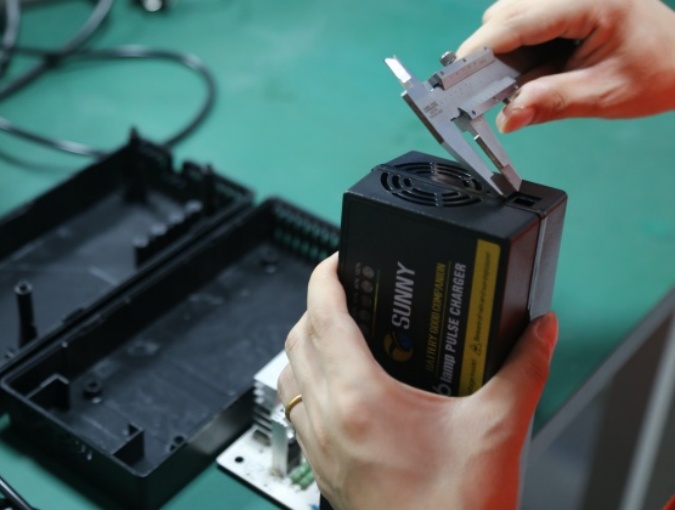 Battery charger housing inspection verifying PCB fit, connector openings, cable routing, and assembly accuracy for custom projects.