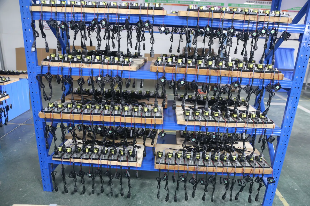 Exposed charger PCB assemblies with attached cables and fans arranged on a blue rack at Linjia.